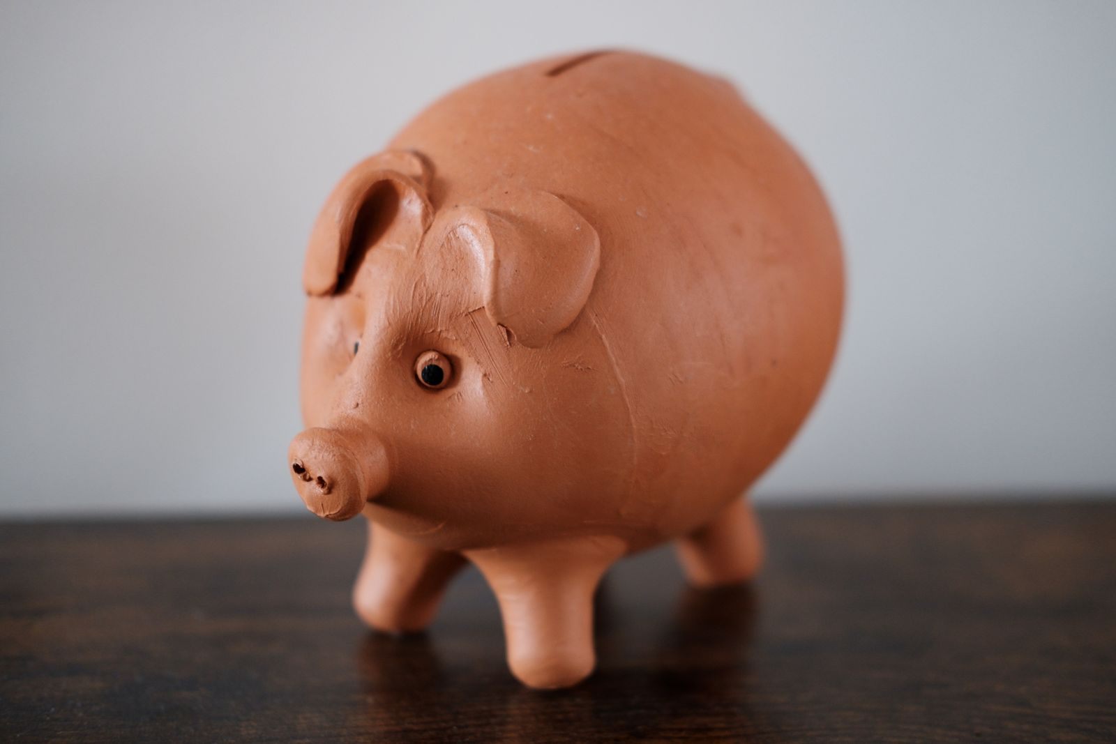 A terracotta piggy bank on a wooden table, the start of a cruise budget