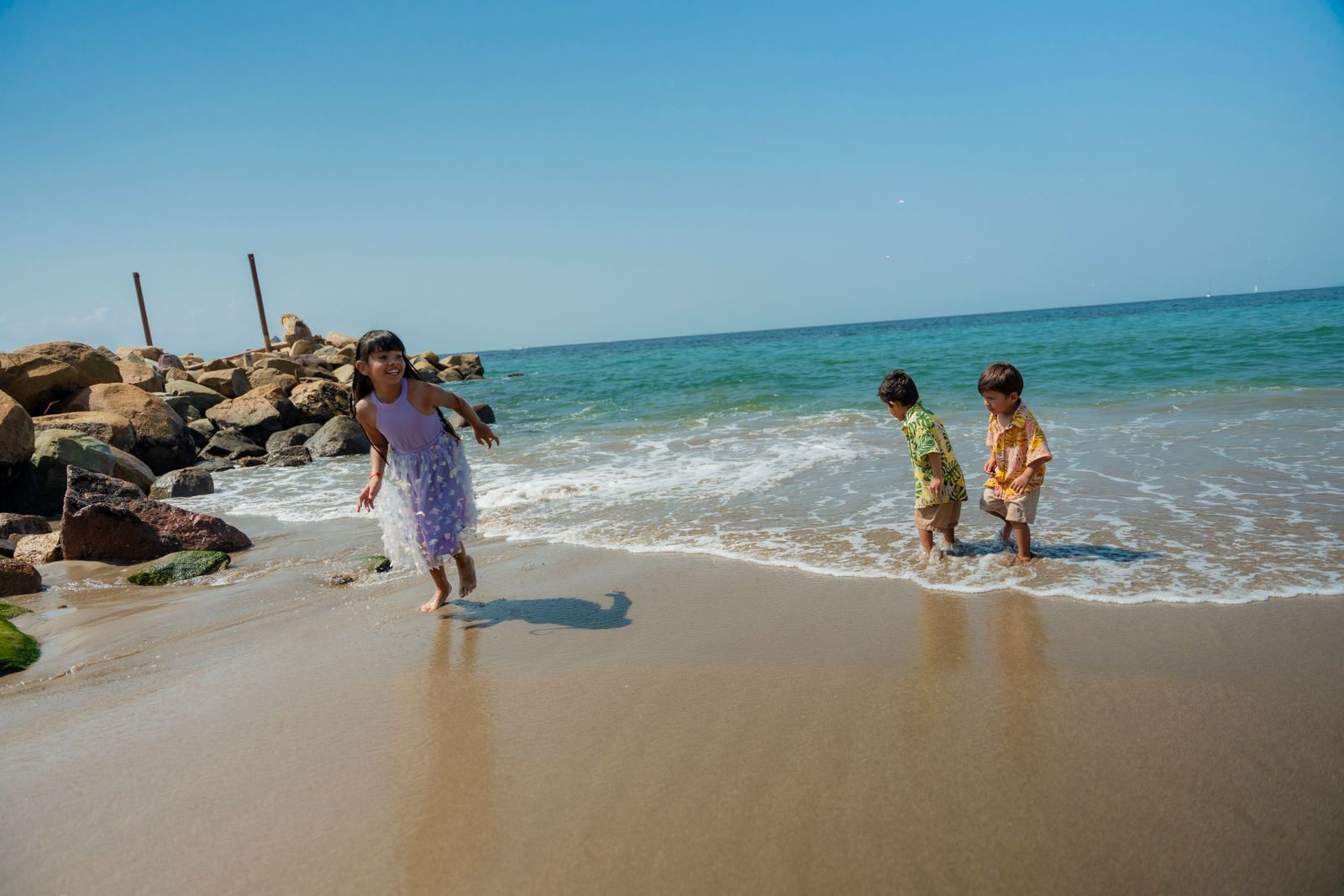 Children running along the edge of the sea on a sunny beach, the kind of day a family of 4 cruise budget is built around